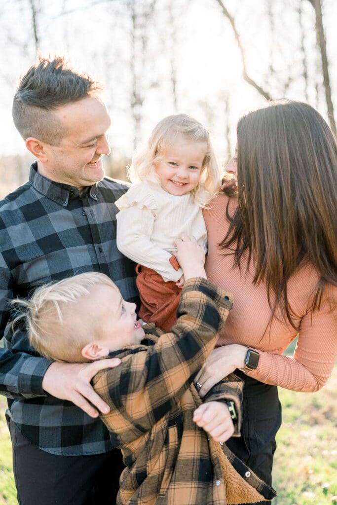 Family of four, big brother tickling little sister
