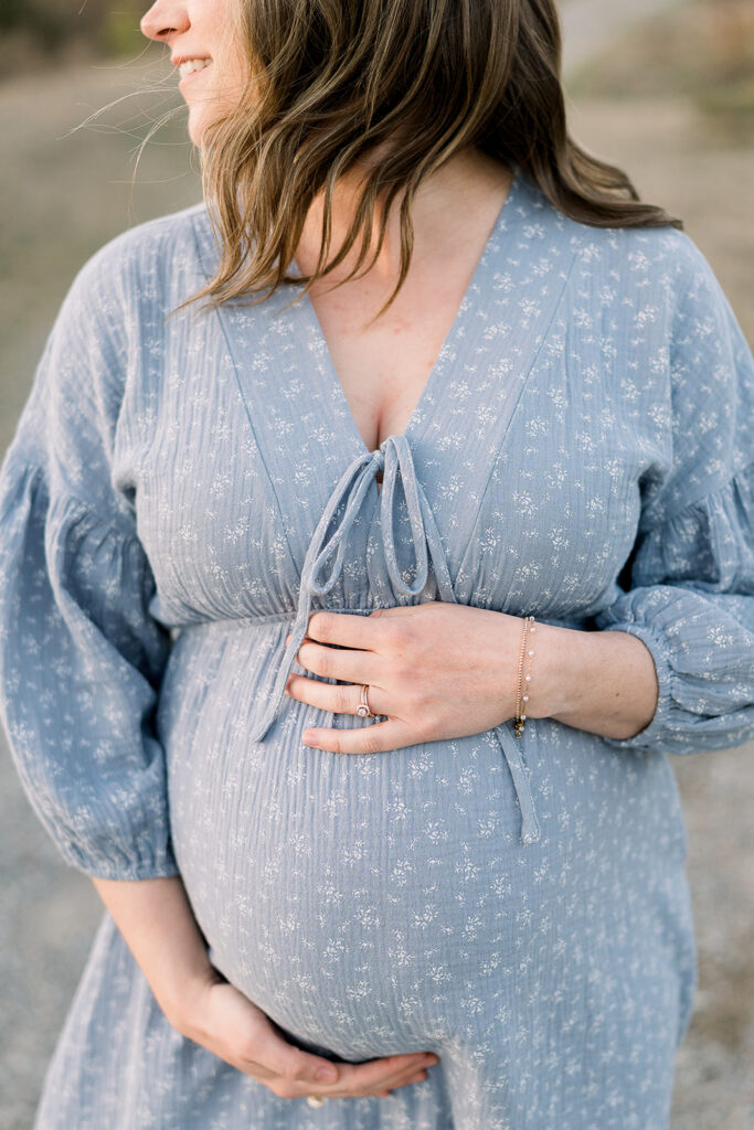 Expecting mother with hands on her belly, hair blowing in the wind